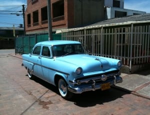 blue classic sedan parked near house during daytime thumbnail