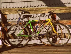 yellow and green cruiser bicycle on brown wooden fence thumbnail
