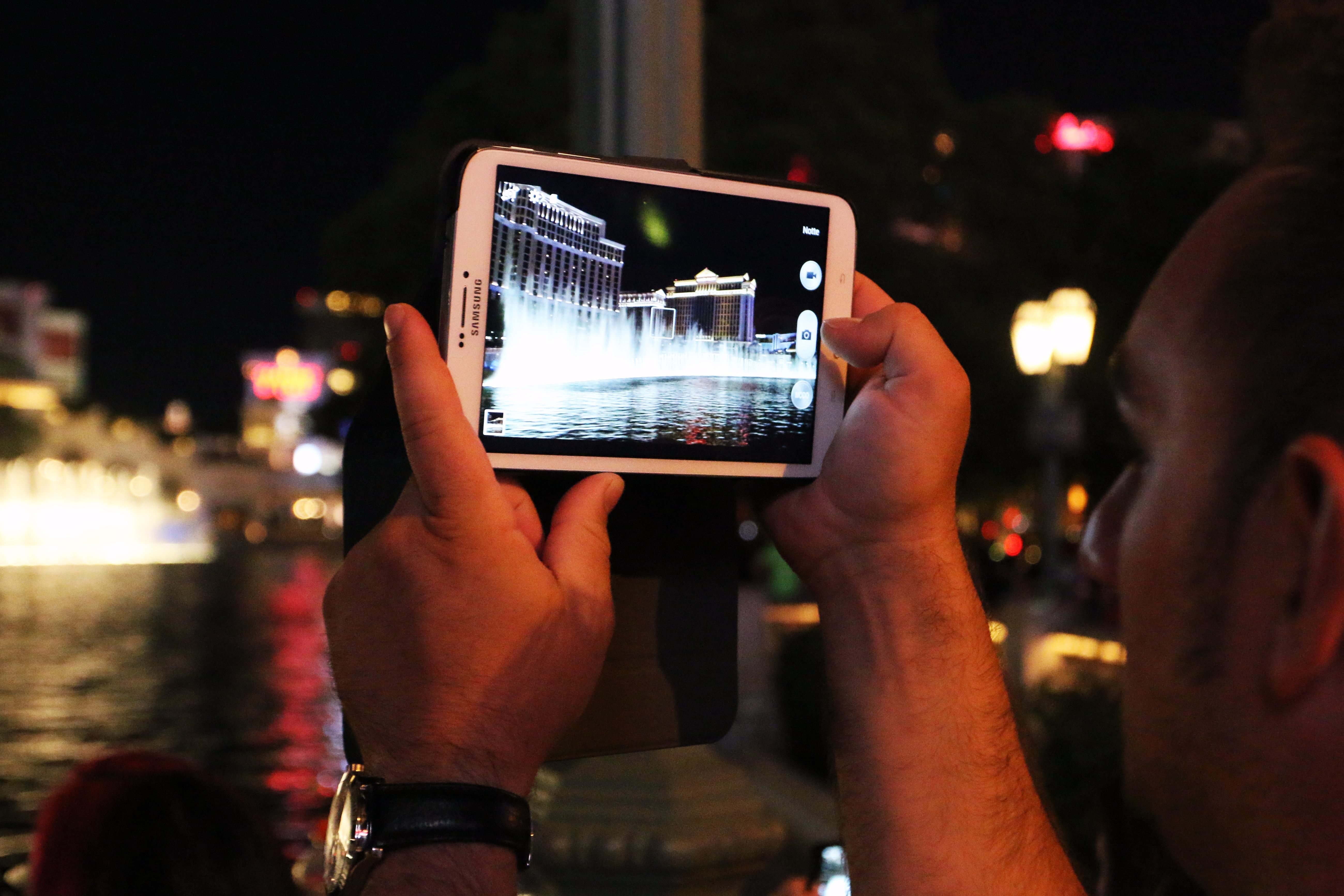 man taking photo using white tablet computer during night time