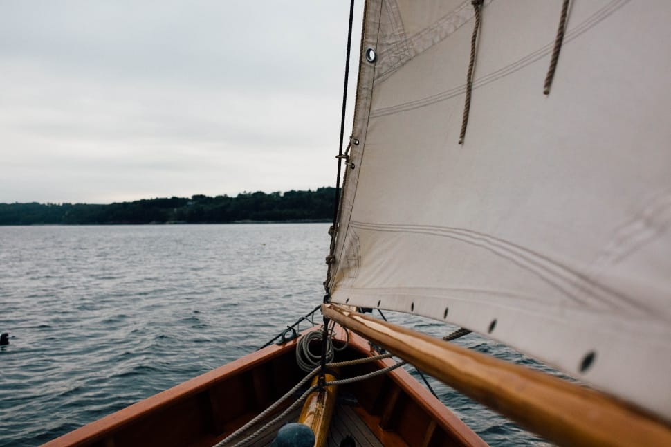 brown sail boat on body of water near island preview