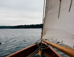 brown sail boat on body of water near island thumbnail