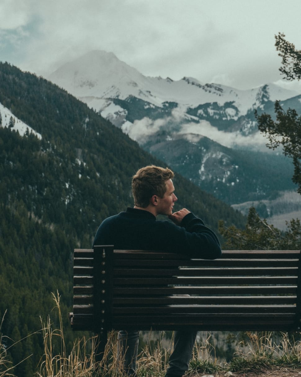 man sitting on bench over looking mountain preview