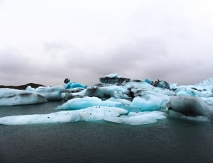 ice glaciers tinted with blue hue near body of water thumbnail