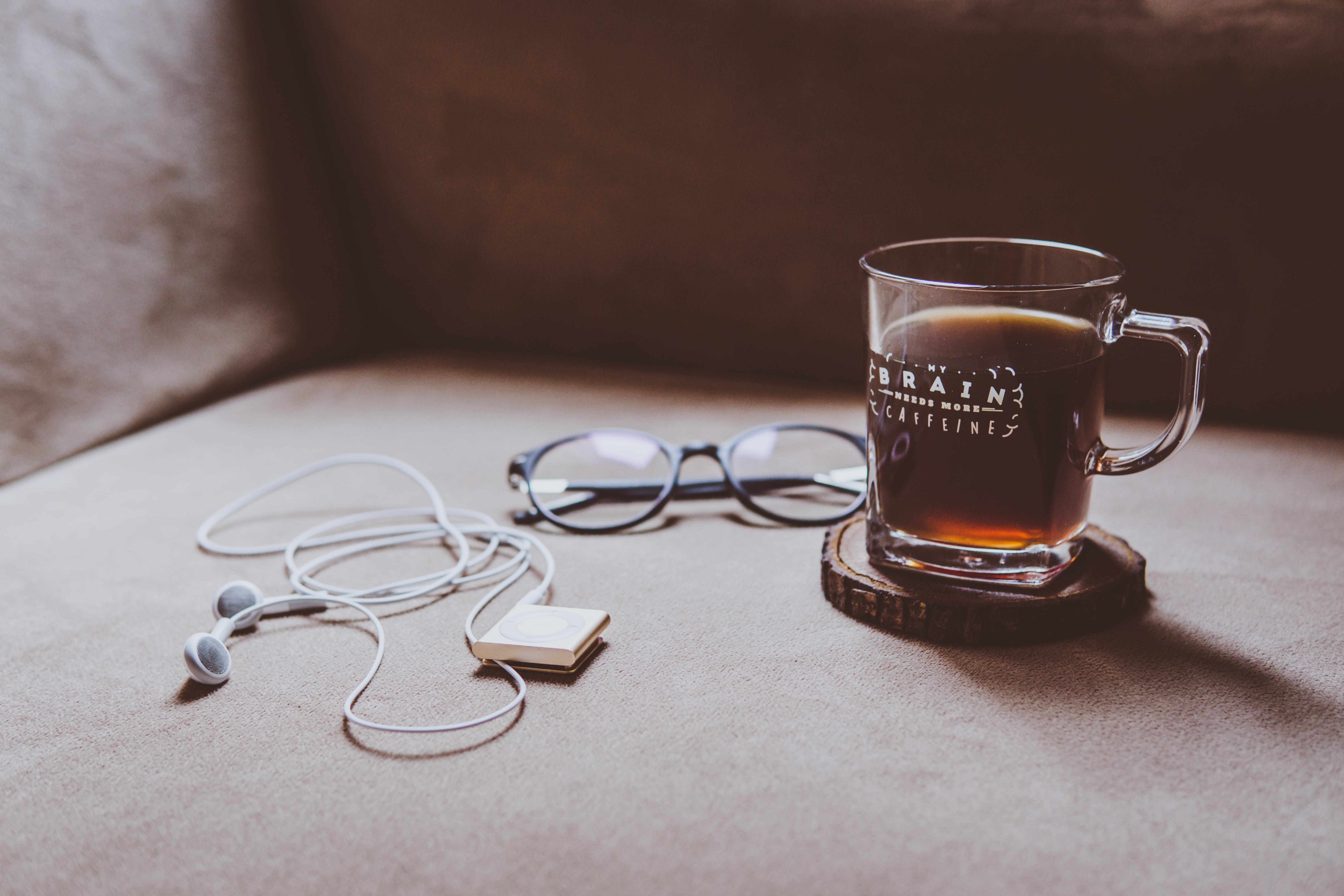 clear mug with coffee beside black frame eyeglasses