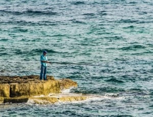 man in blue button-up shirt fishing on the ocean thumbnail
