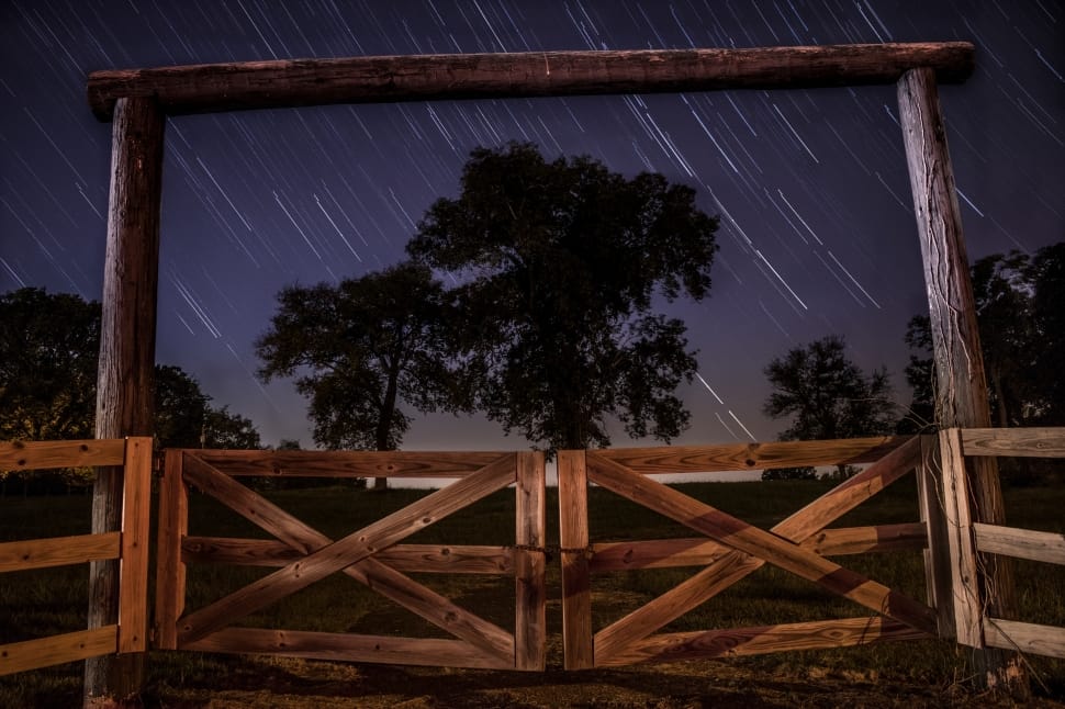 brown wooden barn gate near green leaved trees during nighttime preview