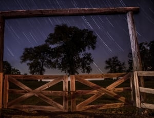 brown wooden barn gate near green leaved trees during nighttime thumbnail