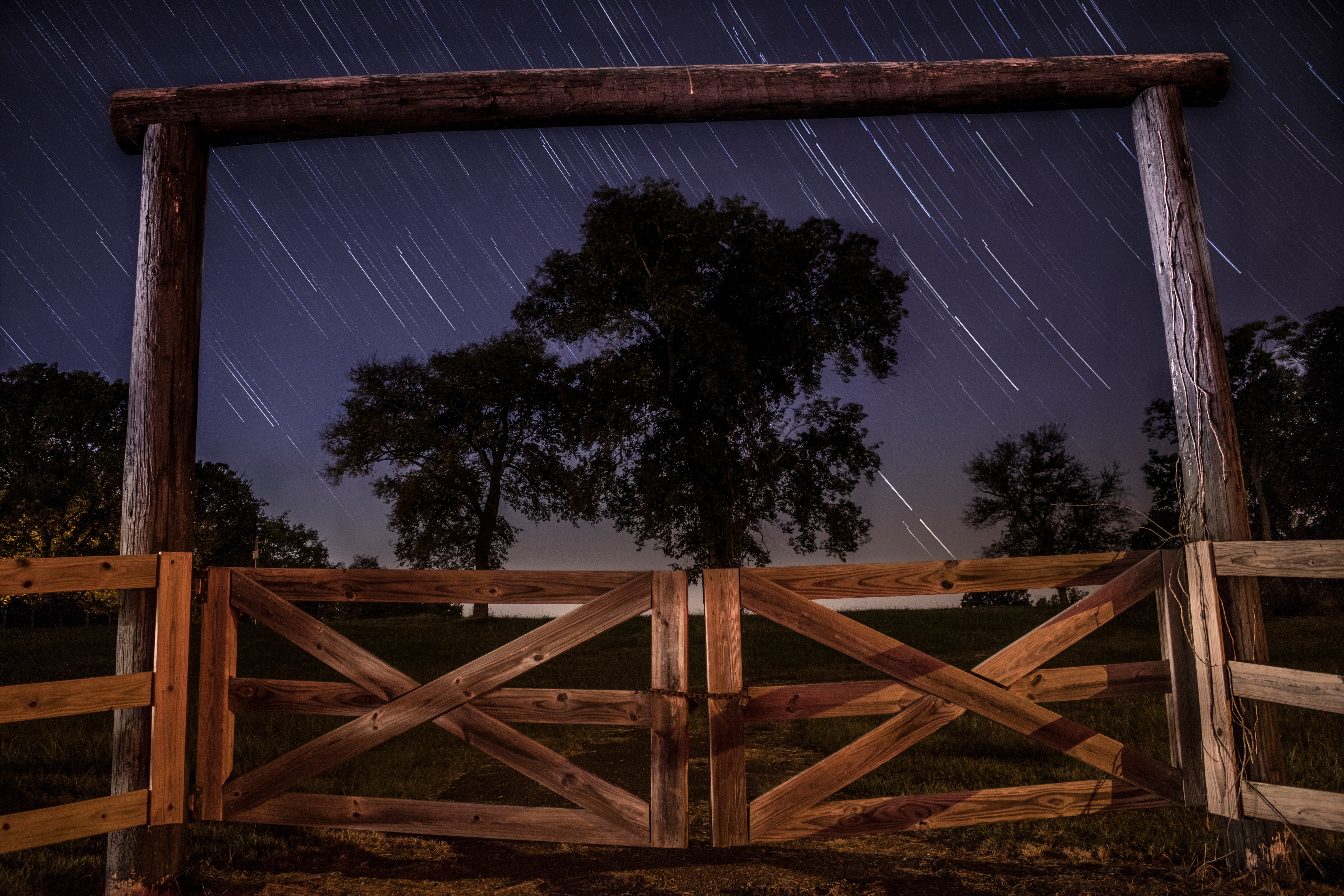 brown wooden barn gate near green leaved trees during nighttime