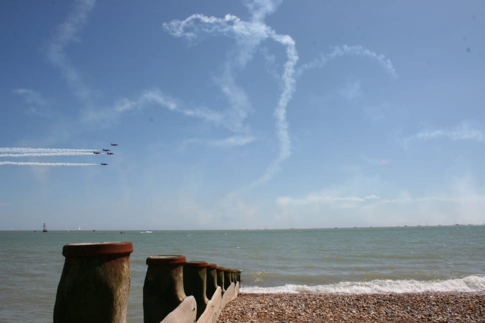 five jetplane with contrails performing near body of water during daytime preview
