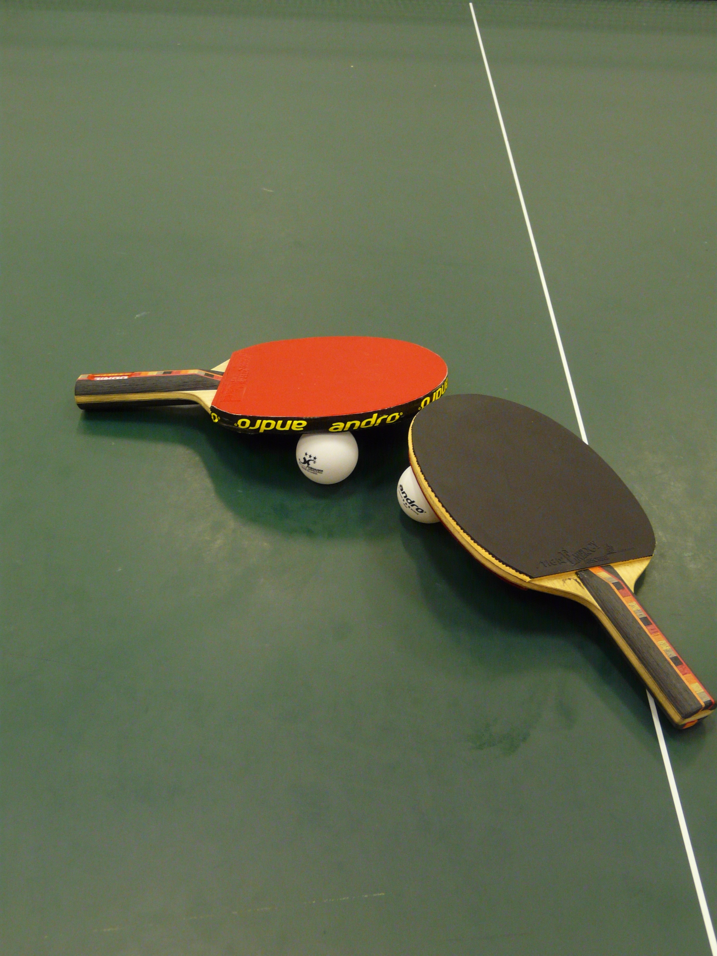 black and red table tennis paddles and balls