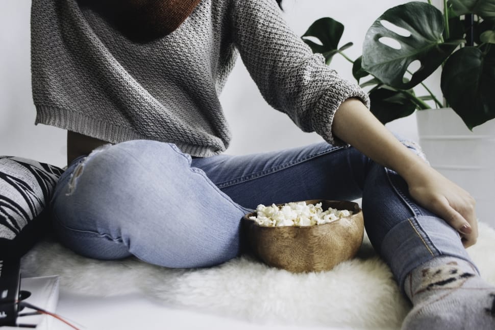 person in blue distress denim sitting on white fur textile beside green plant preview