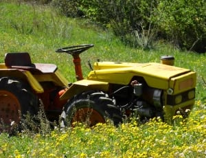 yellow, red, and black tractor in green grass thumbnail