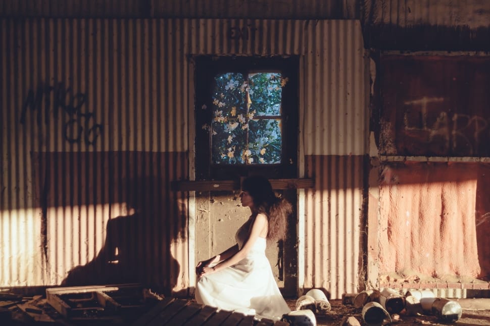 woman wearing white dress kneeling beside corrugated sheet preview