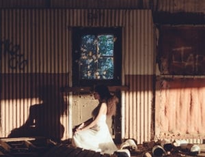 woman wearing white dress kneeling beside corrugated sheet thumbnail