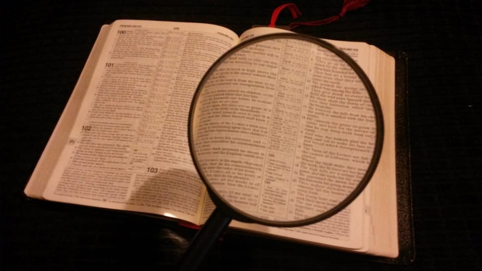black handle magnifying glass with white labeled book preview