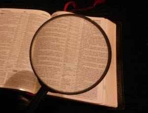 black handle magnifying glass with white labeled book thumbnail