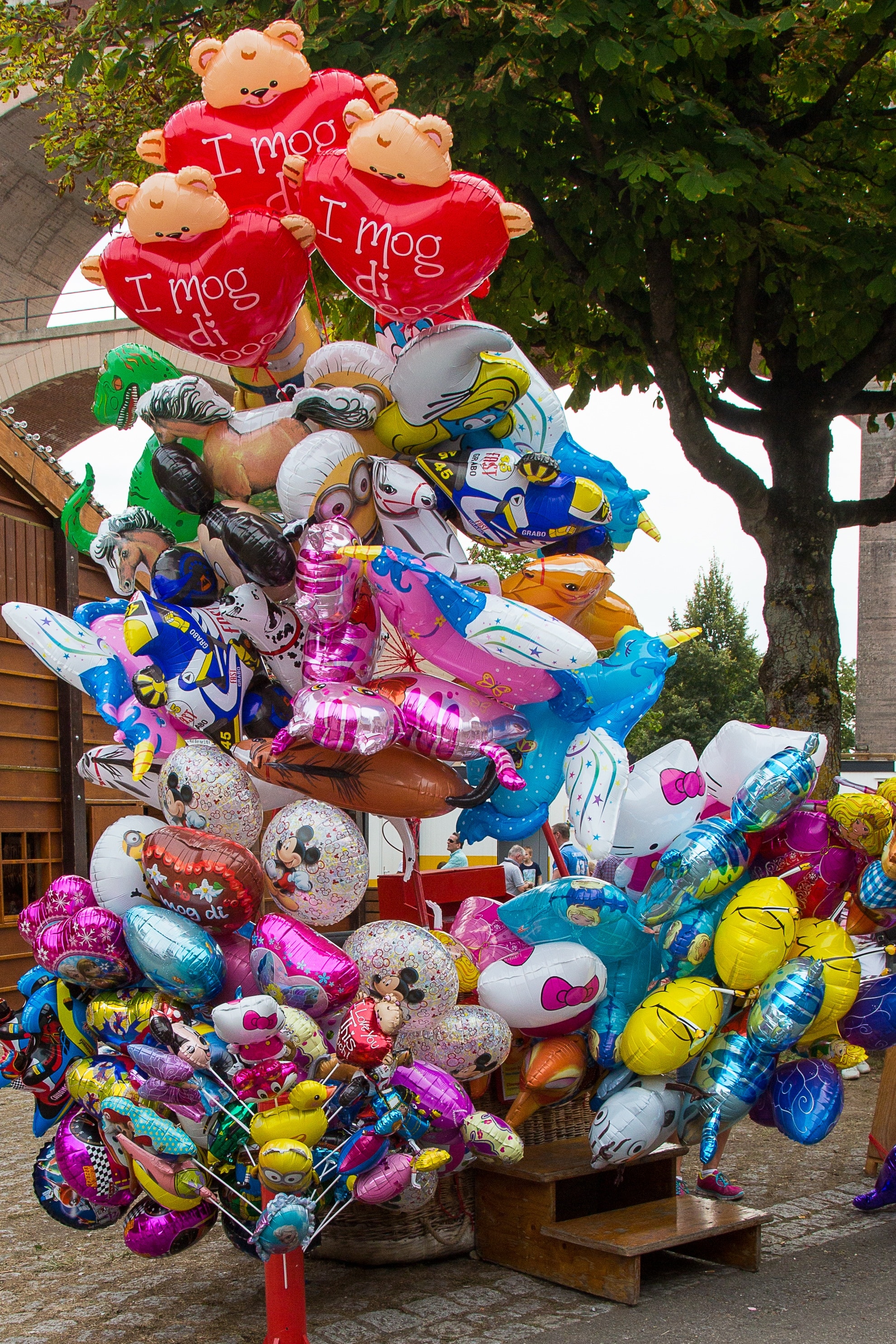 assorted balloons near green leaf tree during daytime