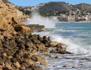 brown rock lot beside wave crash of beach thumbnail