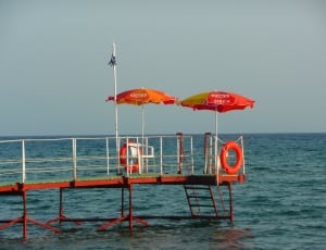 two red-and-yellow parasol umbrella near ocean thumbnail