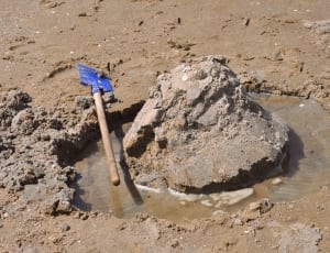 blue and brown handled shovel and brown sand thumbnail