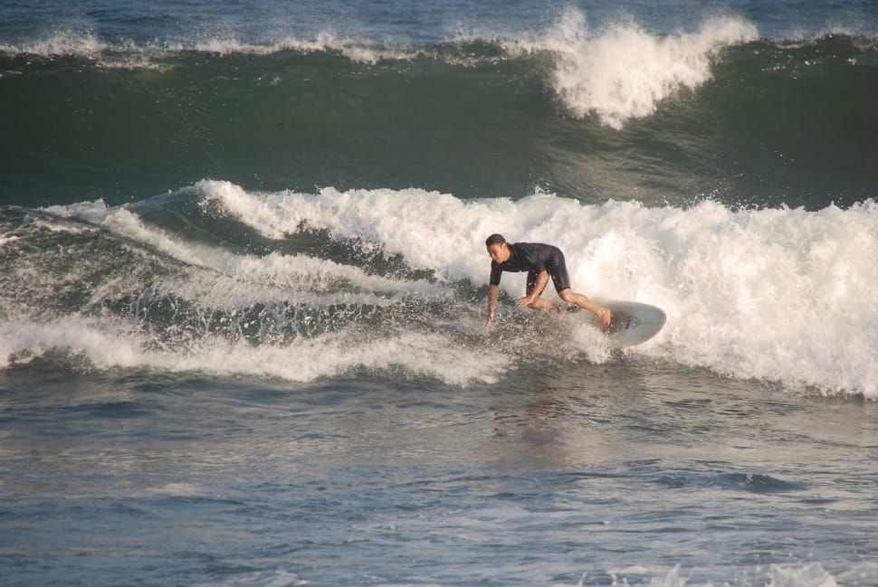 man in white wet suit riding surfboard during daytime preview