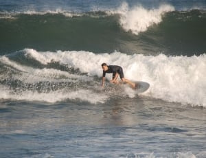 man in white wet suit riding surfboard during daytime thumbnail