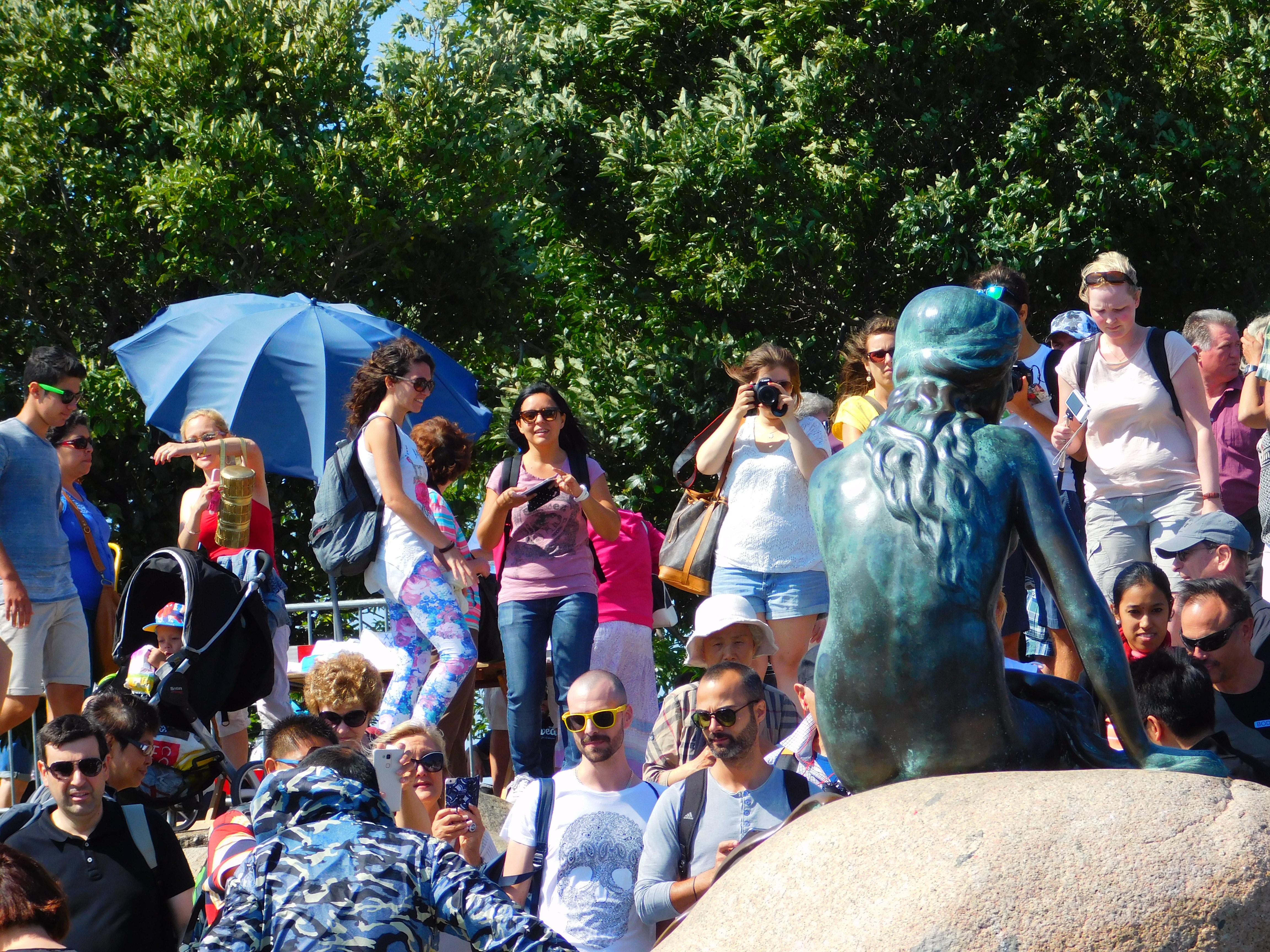 group of people beside the little mermaid statue photo during day time