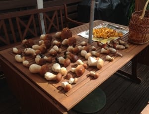 white and white mushrooms on top of brown wooden patio table with basket thumbnail