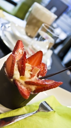 selective focus of sliced strawberry in white cream near stainless steel fork thumbnail