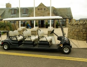 black golf cart with 6 seater parked near building thumbnail