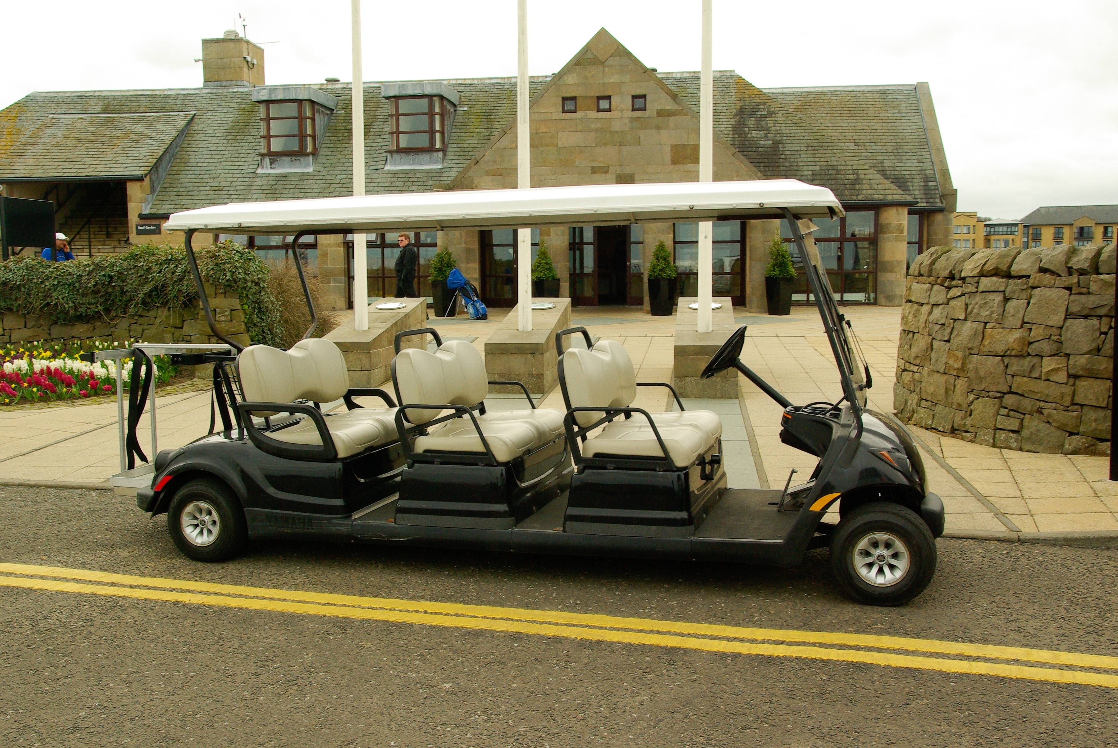 black golf cart with 6 seater parked near building