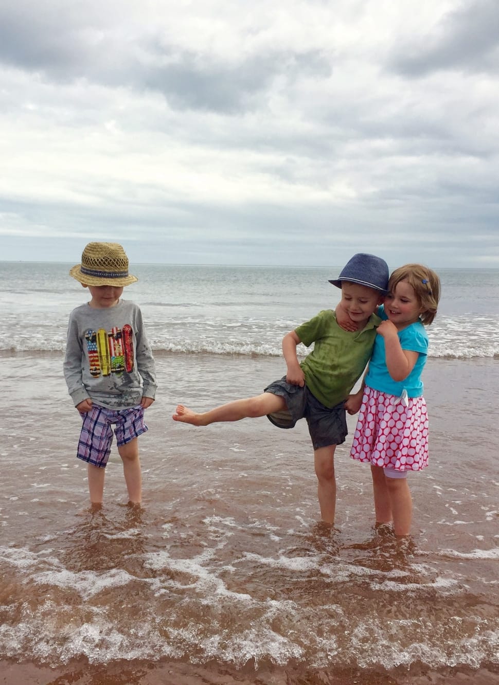 3 children standing in the sand beside beach preview