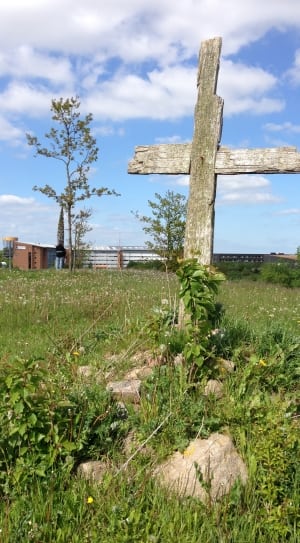 gray wooden cross surrounded by green grass during daytime thumbnail