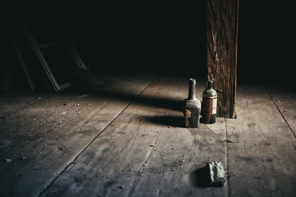two bottles on floor near wooden post preview