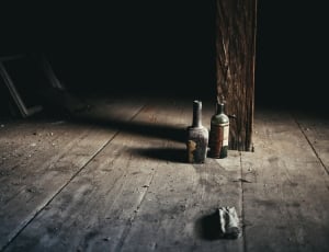 two bottles on floor near wooden post thumbnail