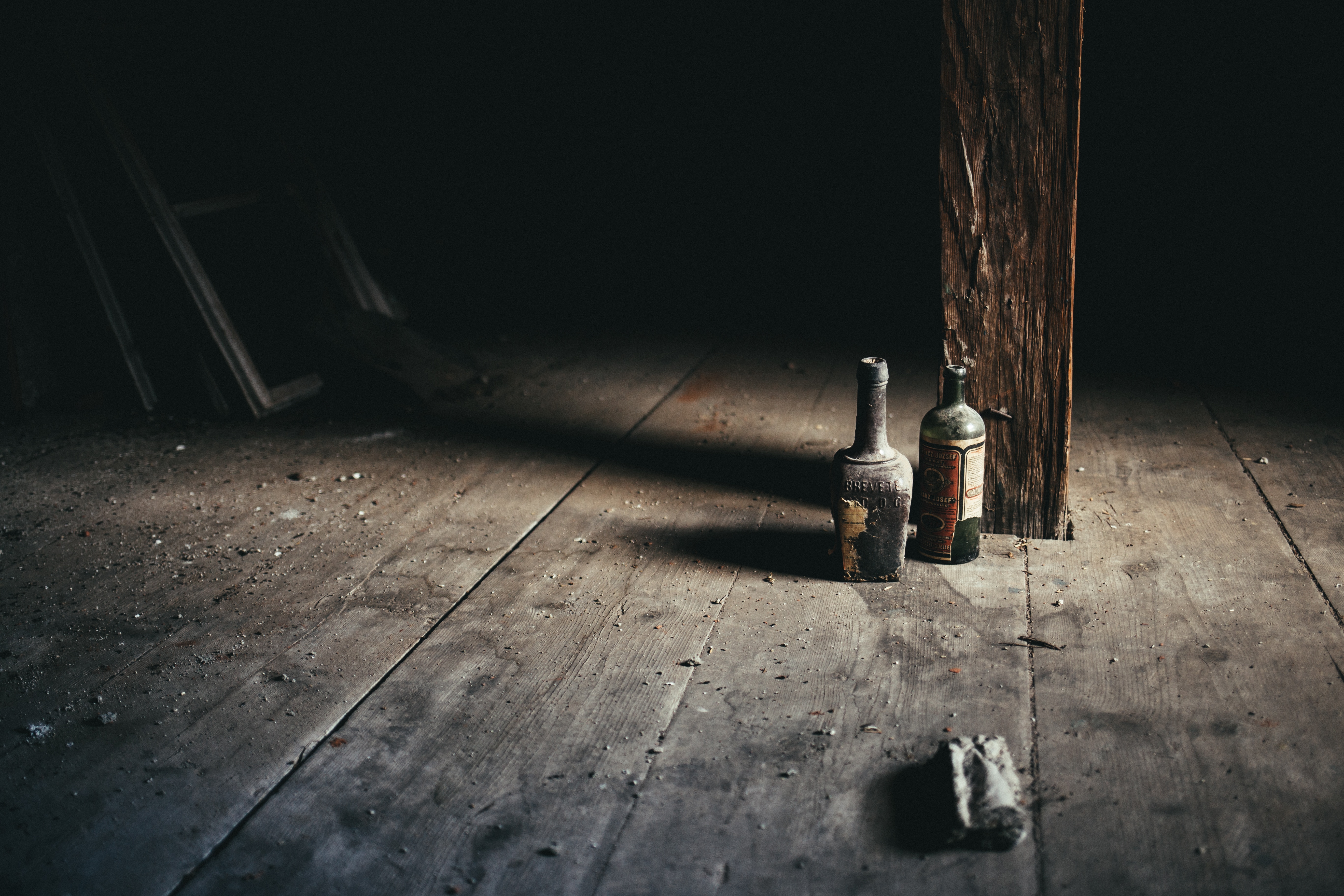 two bottles on floor near wooden post