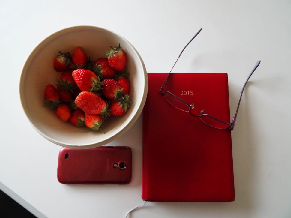 strawberry on ceramic bowl;red smartphone;red 2015 print book;red framed eyeglasses preview