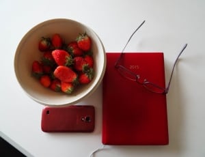 strawberry on ceramic bowl;red smartphone;red 2015 print book;red framed eyeglasses thumbnail
