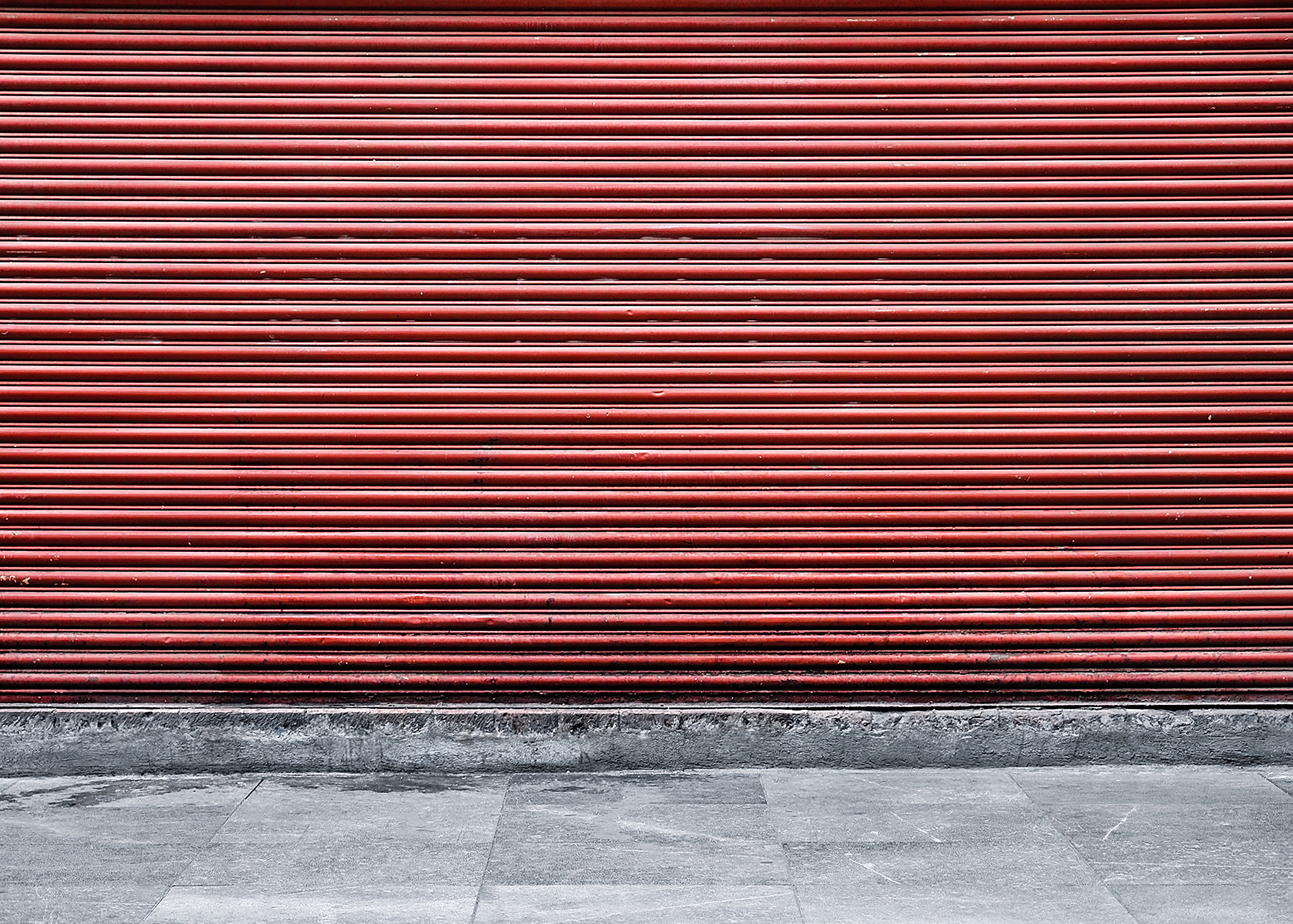 gray concrete pavement beside the red wall