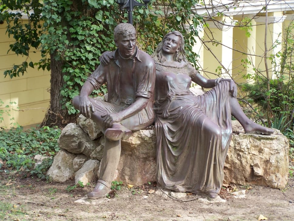brown ceramic male and female sitting on stone statue preview