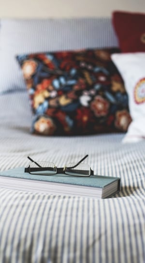 black framed eyeglasses on top of blue covered book thumbnail