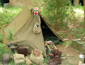 green fabric tent and army helmet thumbnail