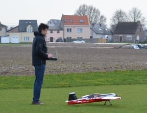 man in black jacket using controller with plane toy thumbnail