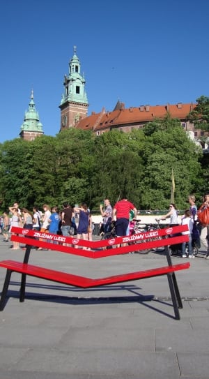 red and black wooden bench in front of group of people during daytime thumbnail