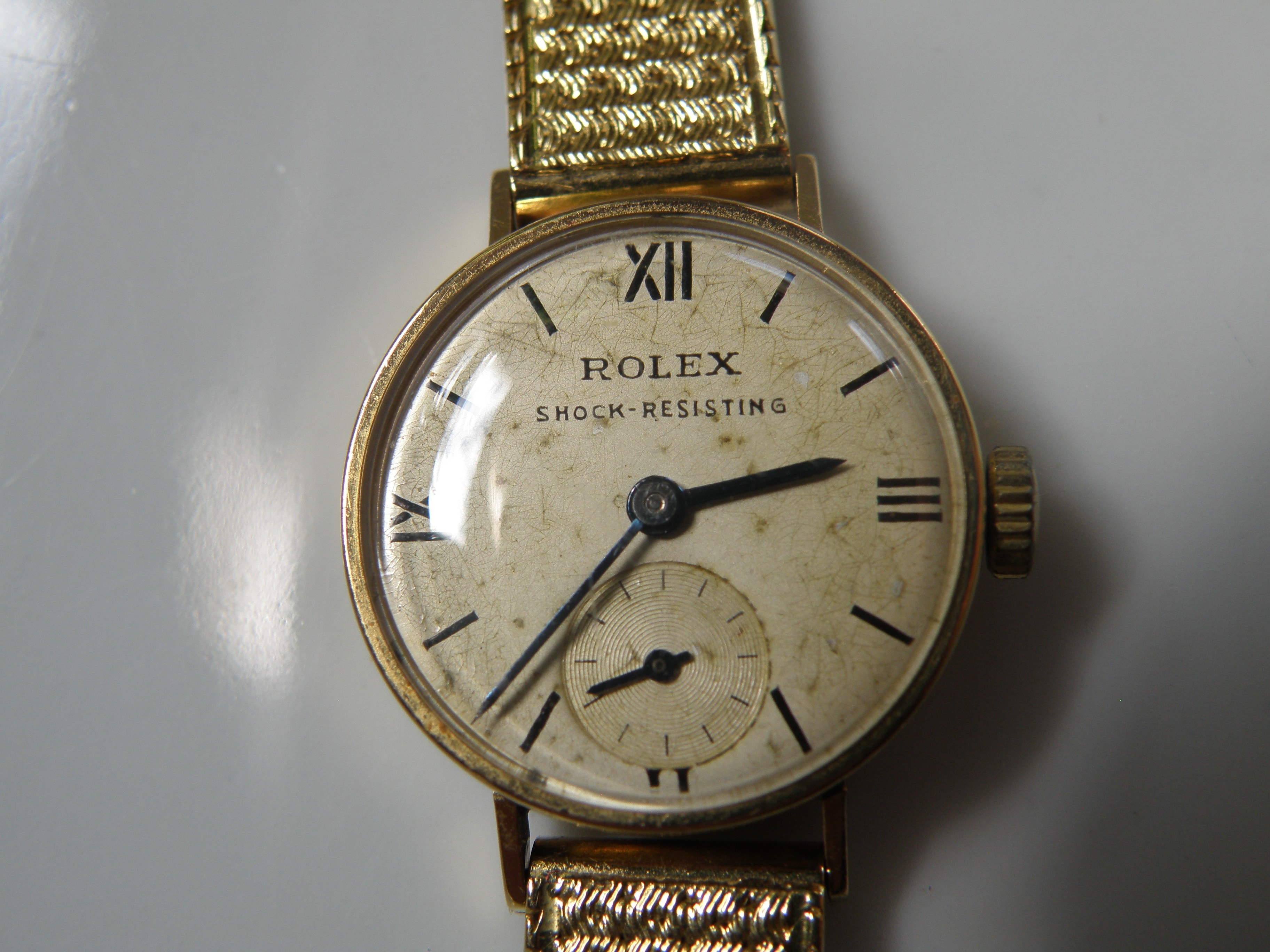round Rolex analog watch with gold link bracelet