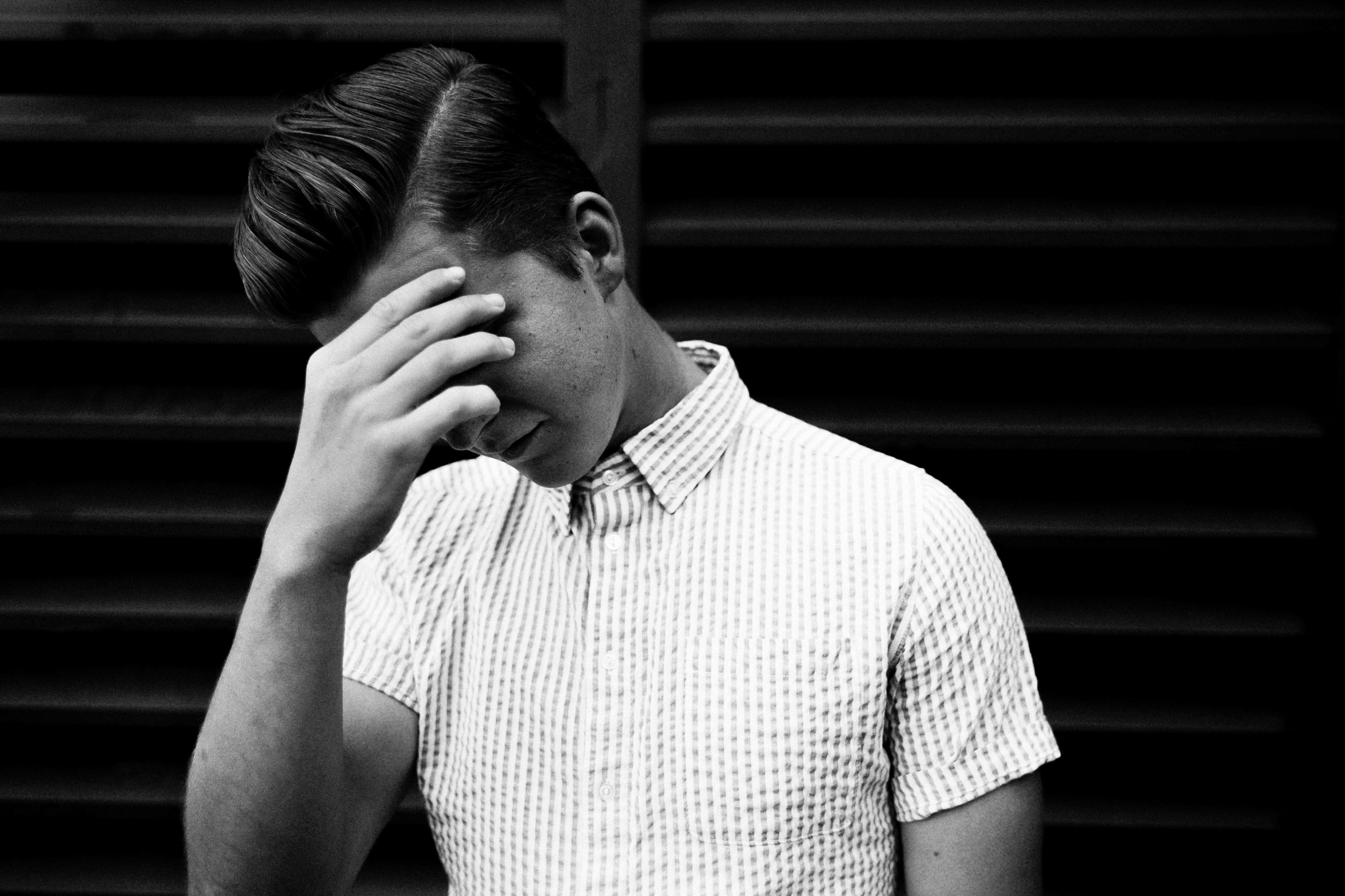 man in collared shirt with face palm in grayscale photo