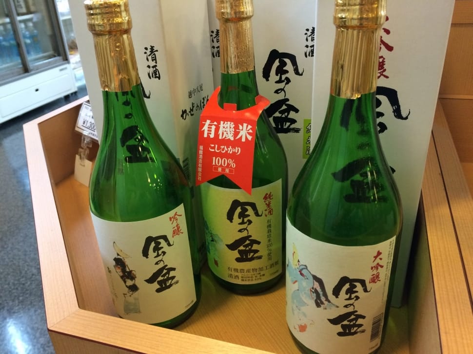 three sake glass bottles near white boxes preview