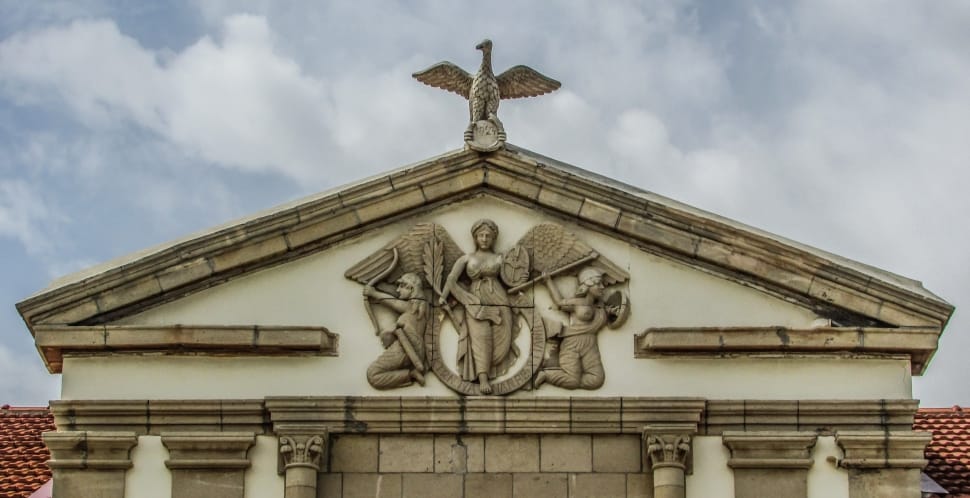 photo of three angel embossed on beige concrete building under white clouds preview