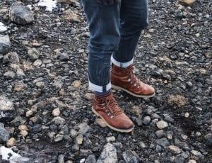 person wearing brown lace up shoes on rock dirt floor during daytime thumbnail