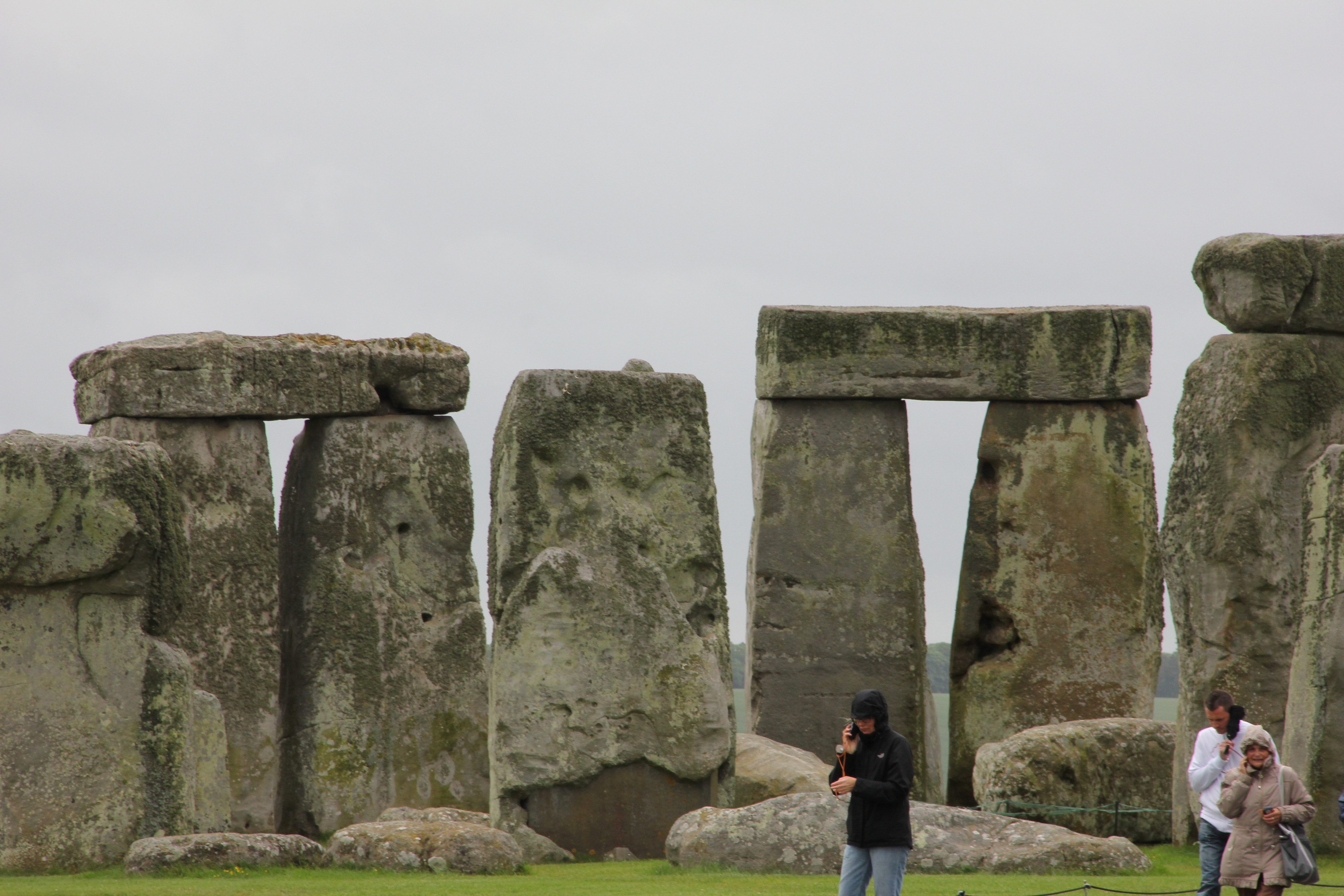person wearing black jacket and blue jeans standing near stonehenge